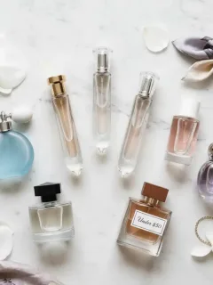 Varias botellas de perfume, de lujo y económicas, dispuestas elegantemente con una etiqueta de precio 'Menos de 50€'.