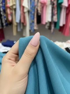 Mano inspeccionando la textura y calidad de una tela de ropa para principiantes en SHEIN.