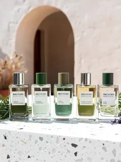 Frascos de perfume sostenible elaborados con materiales reciclados y esencias naturales, en un entorno elegante y ecológico.