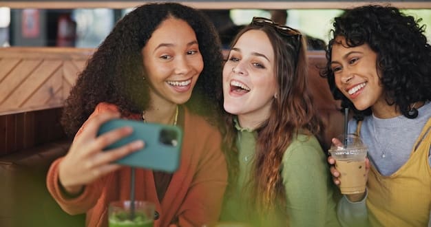 A person putting their phone away and smiling, surrounded by friends in a relaxed, outdoor setting.
