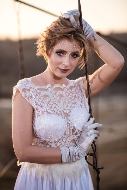 A close-up shot of a celebrity bride wearing an exquisite wedding dress. The dress is adorned with intricate lace detailing, shimmering crystals, and delicate embroidery. The bride's radiant smile adds to the overall allure of the image.