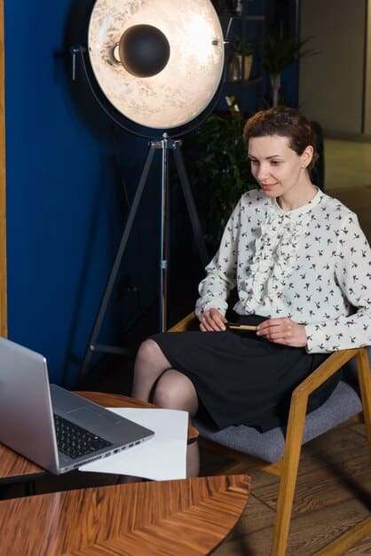 A publicist sitting in a modern office, reviewing a celebrity's social media strategy on a laptop. There are mood boards with celebrity photos and PR campaign ideas on the walls.