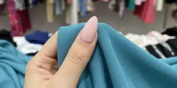 Mano inspeccionando la textura y calidad de una tela de ropa para principiantes en SHEIN.